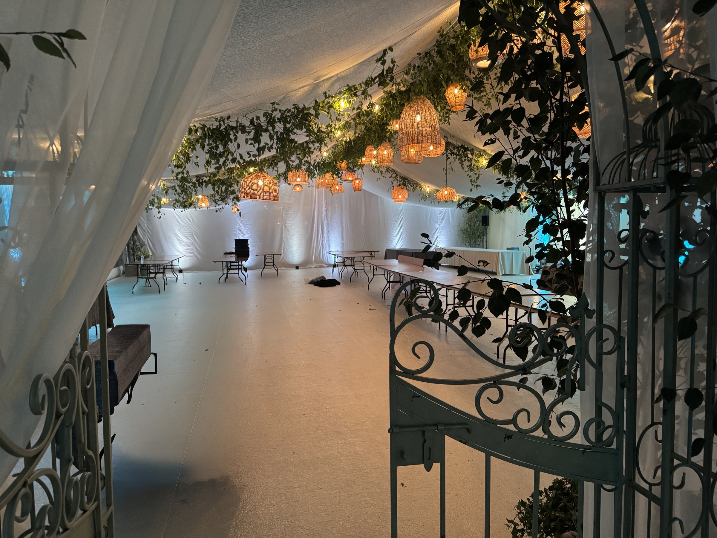 Wedding marquee decorated with greenery and warm woven pendant lights